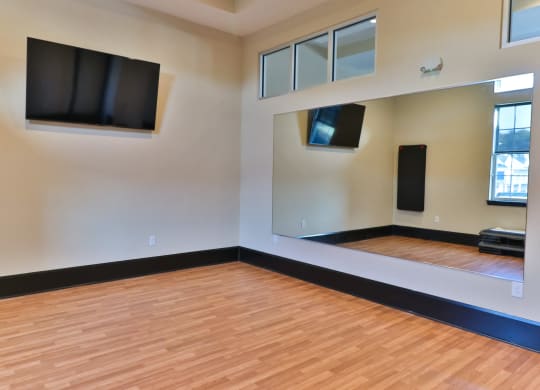 an empty room with wood floors and televisions on the wall