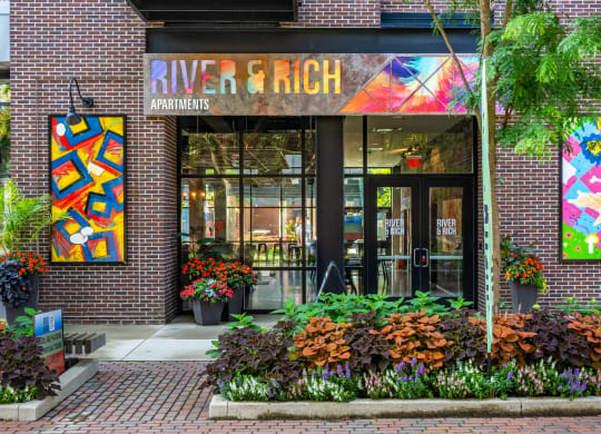 a brick building with a large glass door and colorful paintings on the wall