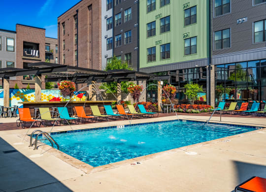 a swimming pool with lounge chairs and umbrellas in front of a building