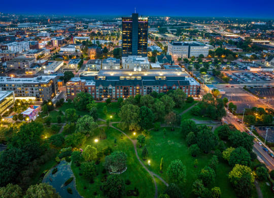 a cityscape at night with a park in the foreground and a tall building in the background