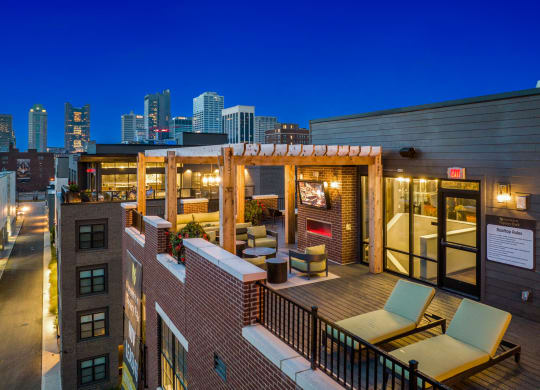 a rooftop deck with lounge chairs and a fireplace with a view of the minneapolis skyline