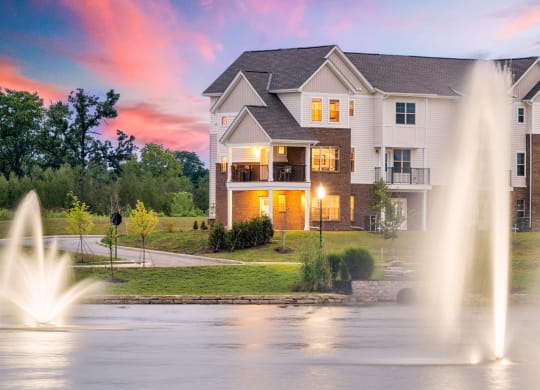 a fountain in front of a house at sunset