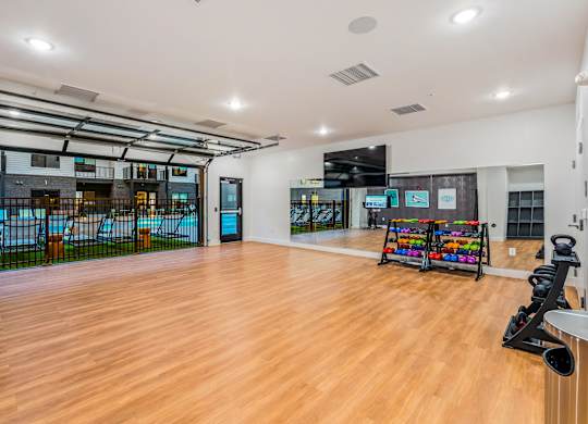 A spacious room with wooden floors and a variety of exercise equipment.