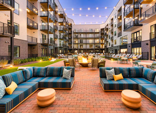 A large blue couch is in the middle of a courtyard surrounded by buildings.