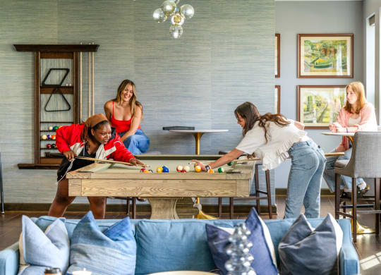 a group of women playing pool in a living room