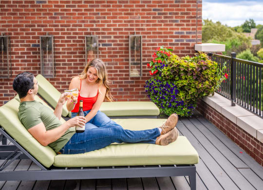 a man and a woman sitting on a couch on a balcony