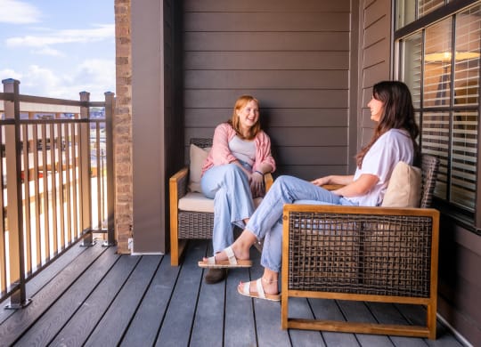 two women sitting on a porch talking