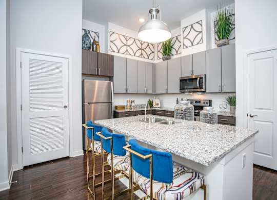 A kitchen with a white countertop and blue barstools.