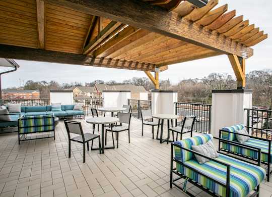 A wooden patio with a striped couch and chairs.