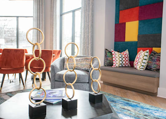 A living room with a grey couch, a red chair, and a coffee table with three golden rings on it.