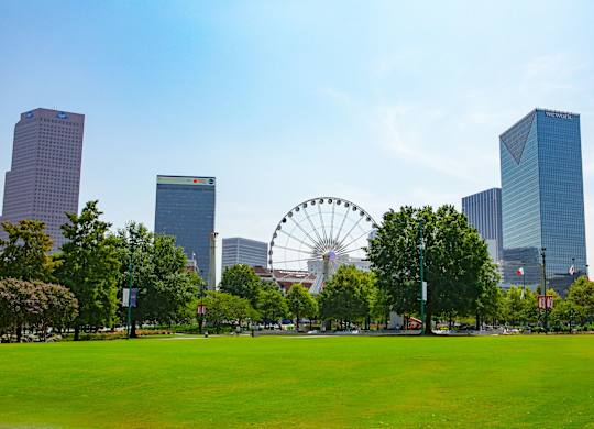 A large Ferris wheel is in the background of a city park.