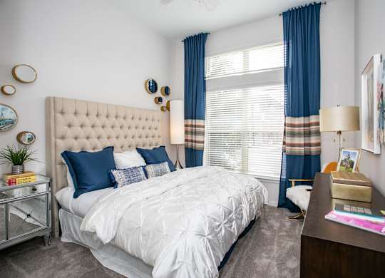 A bedroom with a large bed and a nightstand with a lamp.