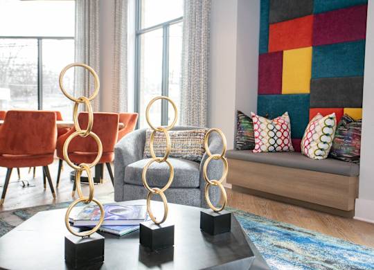 A living room with a grey couch, a red chair, and a coffee table with three golden rings on it.