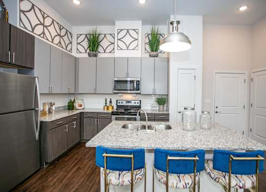 A kitchen with a granite countertop and blue chairs.