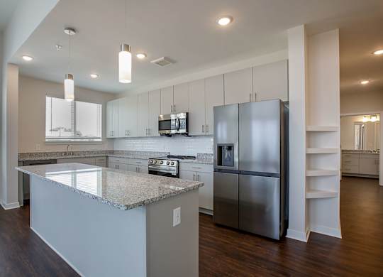 A modern kitchen with a granite countertop and stainless steel appliances.