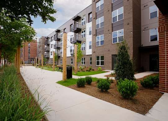 A long concrete walkway leads to a brick building with balconies.
