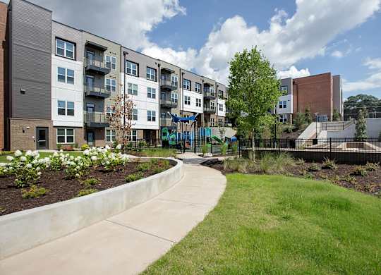 A modern apartment complex with a playground in the foreground.