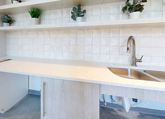A white kitchen with a sink and a cabinet.