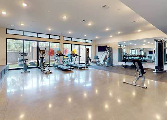 A spacious gym with a variety of equipment and a large mirror on the wall.