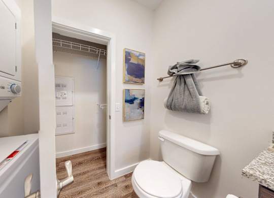 A white dryer is on the left of a white toilet in a small bathroom.