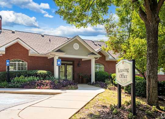 A leasing office is located in a brick building with a landscaped area in front.