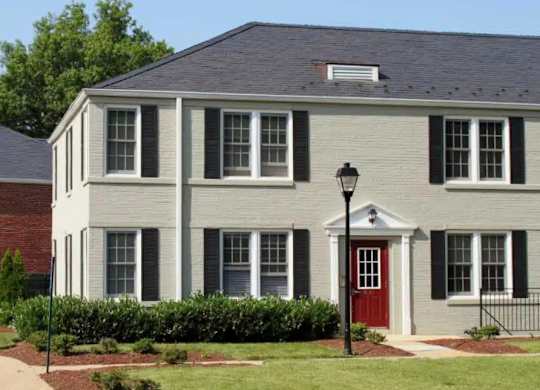 A white house with a red door and black shutters.