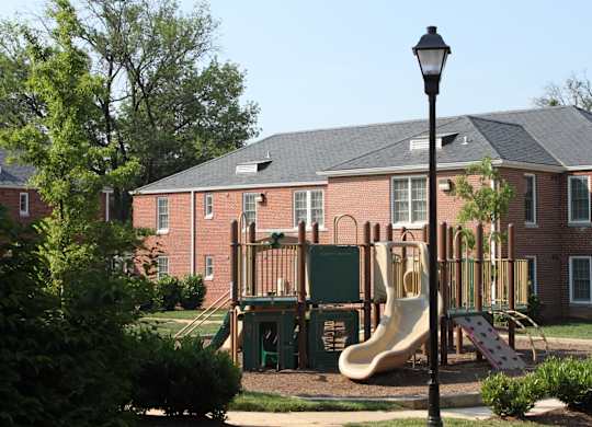 a playground in front of a brick building with a slide