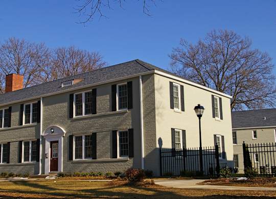 a gray brick house with a white roof and a black fence