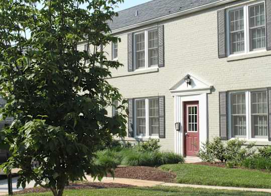 the front of a white brick house with a red door