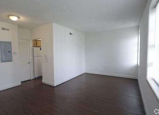 an empty living room with a wood floor and white walls