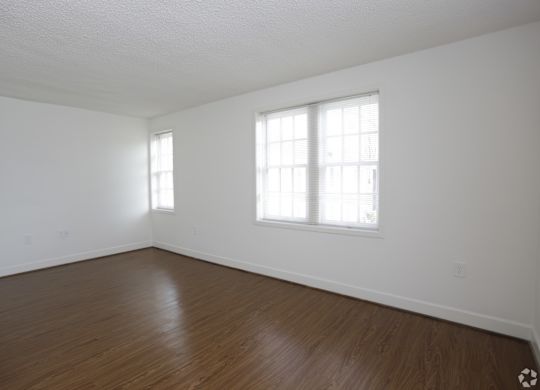 the living room of an empty house with white walls and wood floors