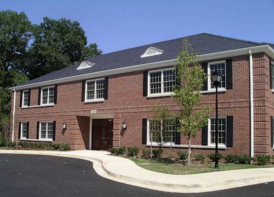 a red brick house with a black roof and a sidewalk