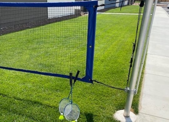 a tennis racket and two tennis balls on the grass next to a fenceat Westbury Apartments, Rancho Cucamonga, 91739
