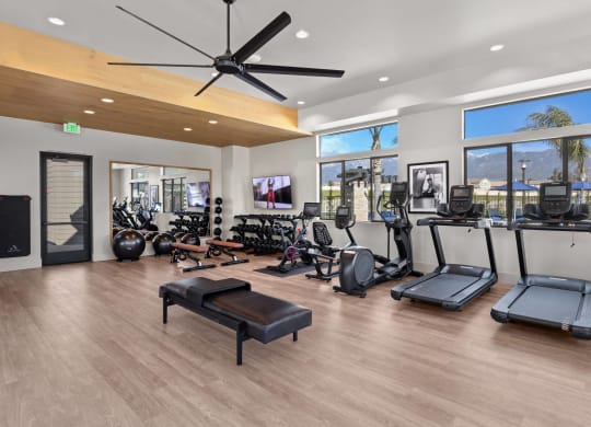 a gym with a lot of exercise equipment and windowsat Westbury Apartments, Rancho Cucamonga, California