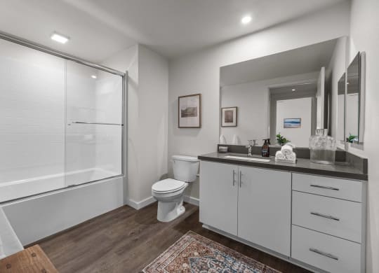 a bathroom with a shower toilet and sink and a mirrorat Westbury Apartments, California
