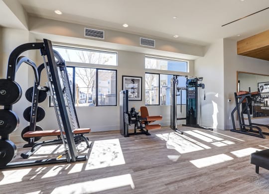 a gym with exercise equipment and windows at the district flats apartments  at Westbury Apartments, Rancho Cucamonga, California