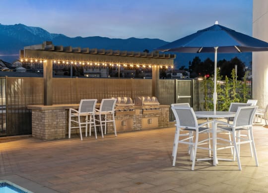 a patio with a bar and tables with chairs and umbrellasat Westbury Apartments, Rancho Cucamonga