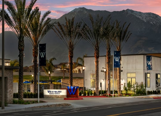 a city street with palm trees and a building with mountains in the backgroundat Westbury Apartments, Rancho Cucamonga, California 