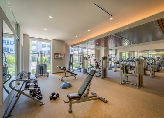 a gym with weights and cardio equipment in a building with glass doors at The Metropolitan Downtown Columbia, Maryland, 21044
