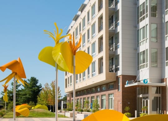 a city street with yellow sculptures in front of an apartment building at The Metropolitan Downtown Columbia, Maryland