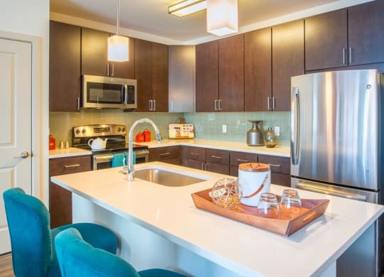 a kitchen with stainless steel appliances and a white counter top at The Metropolitan Downtown Columbia, Columbia, Maryland
