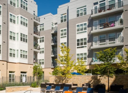 an outdoor patio with tables and chairs in front of an apartment building at The Metropolitan Downtown Columbia, Columbia, MD, 21044