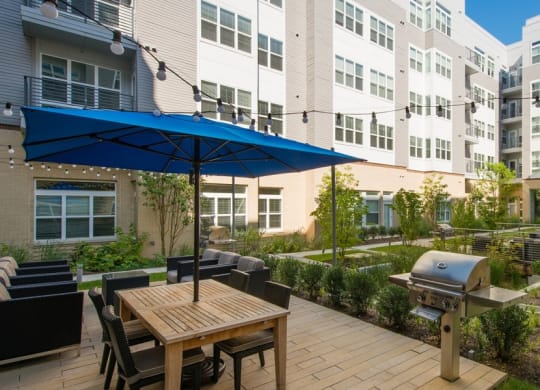 a patio with an umbrella and a table with chairs and a grill at The Metropolitan Downtown Columbia, Columbia, 21044