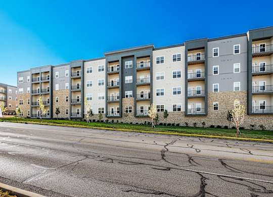 A row of modern apartment buildings with a cracked street in front.