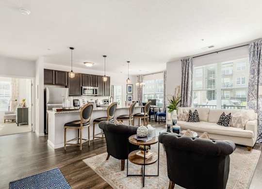 A modern living room with a kitchen in the background.