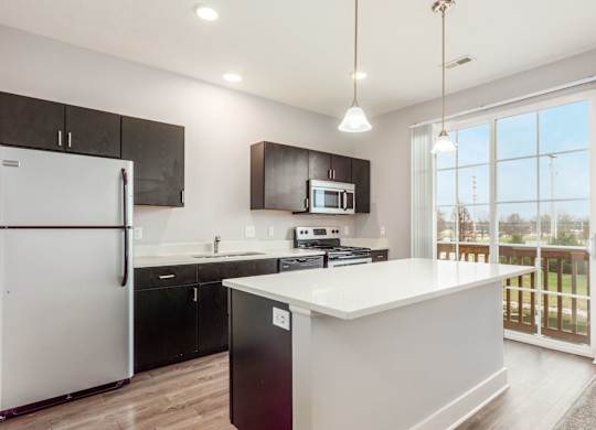 A modern kitchen with a white island and black cabinets.
