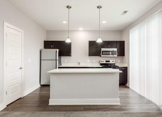 A modern kitchen with a white island and dark brown cabinets.