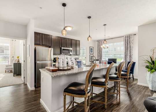 A kitchen with a white island and black chairs.