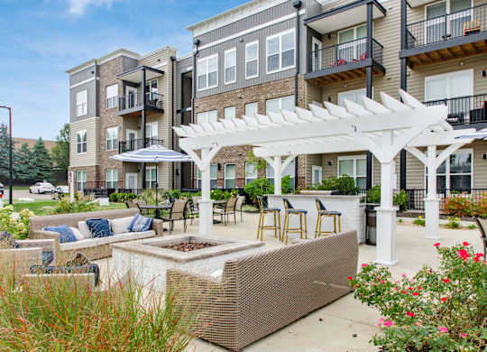 A patio with a white pergola and a planter box is surrounded by apartment buildings.