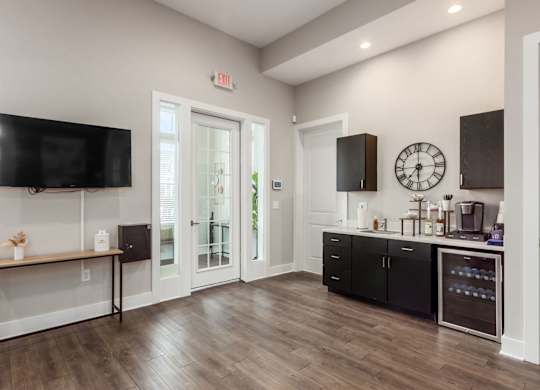 A kitchen with black cabinets and a wooden floor.